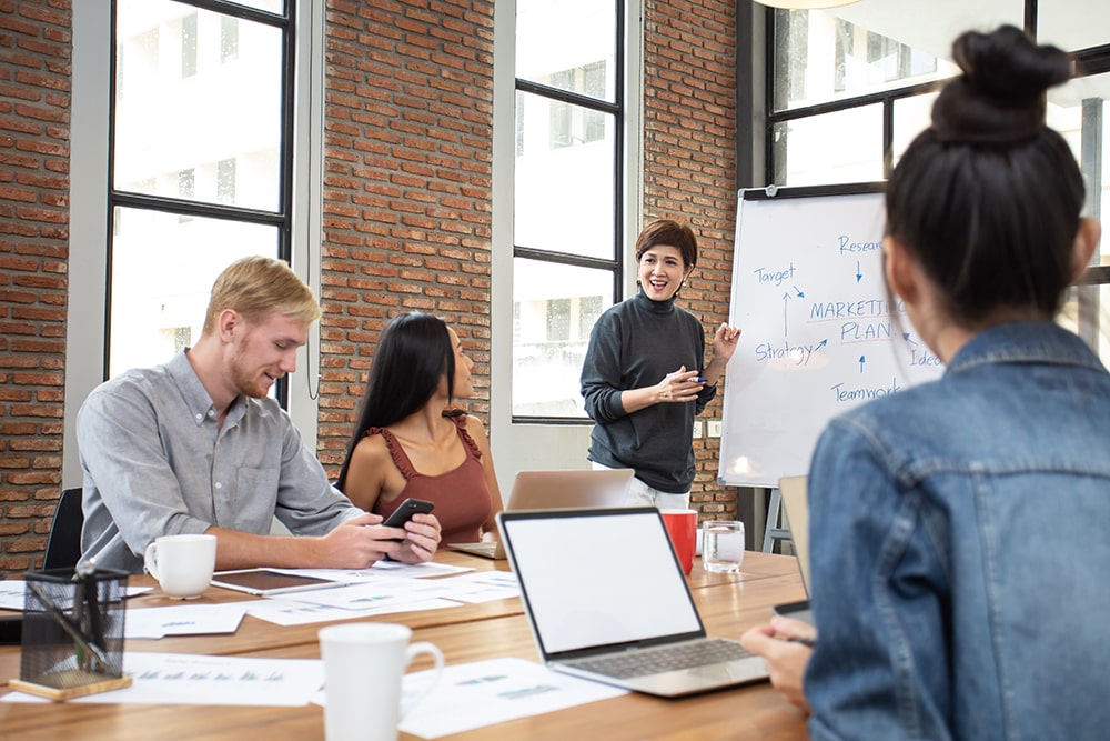 A person teaches colleagues from a whiteboard